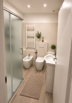 A modern bathroom with a glass shower enclosure, a bidet, a toilet, and a sink. - Heart of Genoa, 5 min from Brignole (Genova)