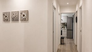 Ein Korridor mit Holzdielen, weißen Wänden und drei an der Wand befestigten Blumenbildern.