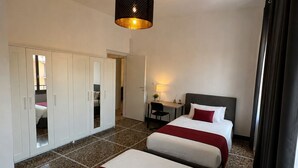 Ein Hotelzimmer mit zwei Betten, einem Schreibtisch, einem Stuhl, einem Kleiderschrank und einer Pendelleuchte.