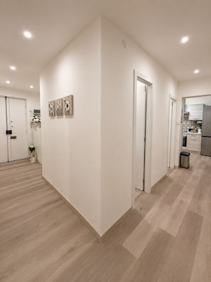 A modern interior with a hallway leading to a kitchen area, featuring light-colored walls and wooden flooring. - Heart of Genoa, 5 min from Brignole (Genova)