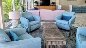 Ein Wohnzimmer mit einer Sofagarnitur, Sesseln, einem Couchtisch und einem Fernseher.