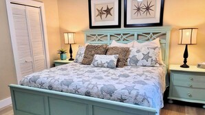Ein Schlafzimmer mit einem Bett, zwei Nachttischen, einer Kommode, einem Kleiderschrank und Wandbildern.