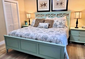 A bedroom with a bed, two nightstands, a dresser, a closet, and wall art. - The Dream House / Gulf Front Luxury Retreat (Marathon)