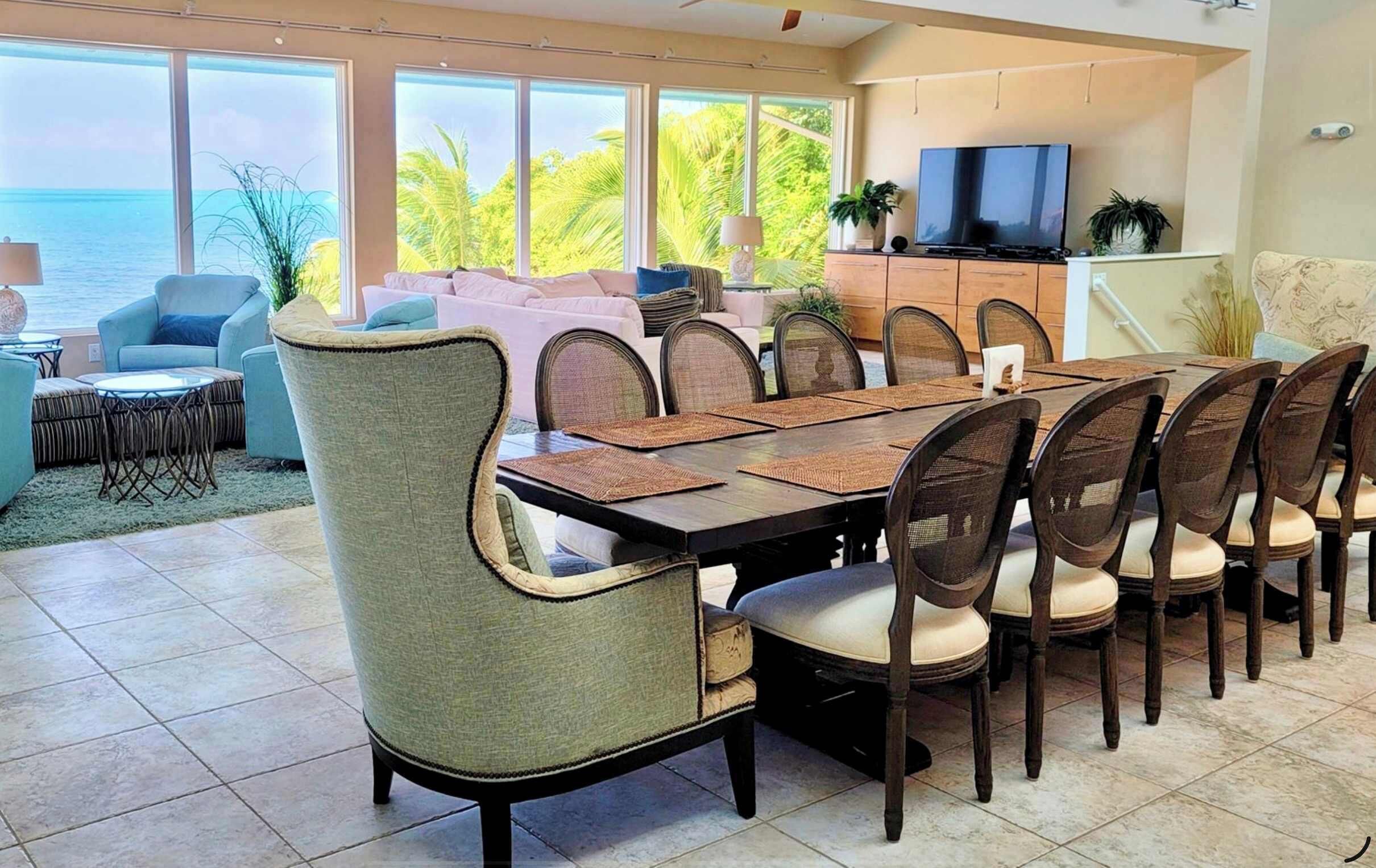 A dining area with a large table, chairs, and a television in the background.
