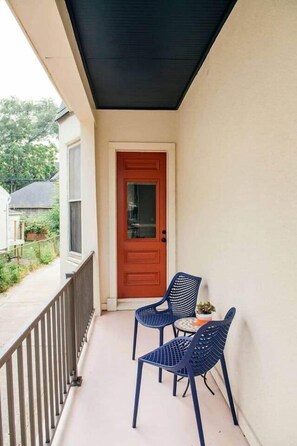 Ein Balkon mit Tür, zwei Stühlen und einem kleinen Tisch.