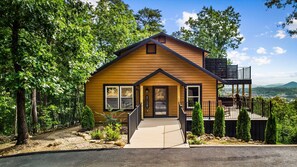 A two-story wooden house with a front porch, a deck, and a view of the surrounding landscape. - NEW Dolly Fireworks View! 3 King, LuxHotTub, Fence Yd (Pigeon Forge)