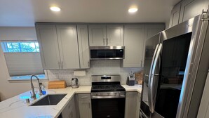 A modern kitchen with stainless steel appliances, grey cabinetry, and a wooden floor. - Cozy 2-bedroom house in Shoreline perfect for relaxing stays (Shoreline)