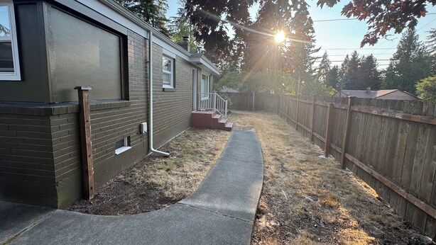A residential property with a paved walkway, a wooden fence, and a house with a brick exterior. - Cozy 2-bedroom house in Shoreline perfect for relaxing stays (Shoreline)