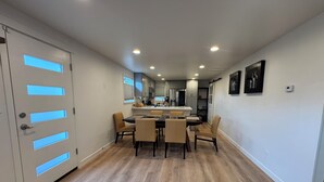 A modern kitchen with a central island, wooden flooring, and a dining area with chairs. - Cozy 2-bedroom house in Shoreline perfect for relaxing stays (Shoreline)