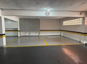 A parking garage with a concrete ceiling, a fire alarm, and a row of lockers.