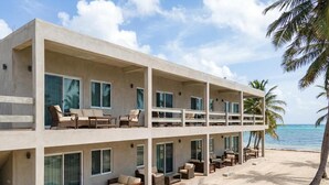 A beachfront hotel with multiple balconies, outdoor seating, and a view of the ocean.