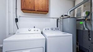 A laundry room with two Whirlpool washers, a cabinet above, and a water heater to the right. - 3/1 Home in Southfield, Near Hospitals & Parks (Southfield)