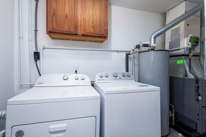 A laundry room with two Whirlpool washers, a cabinet above, and a water heater to the right. - 3/1 Home in Southfield, Near Hospitals & Parks (Southfield)