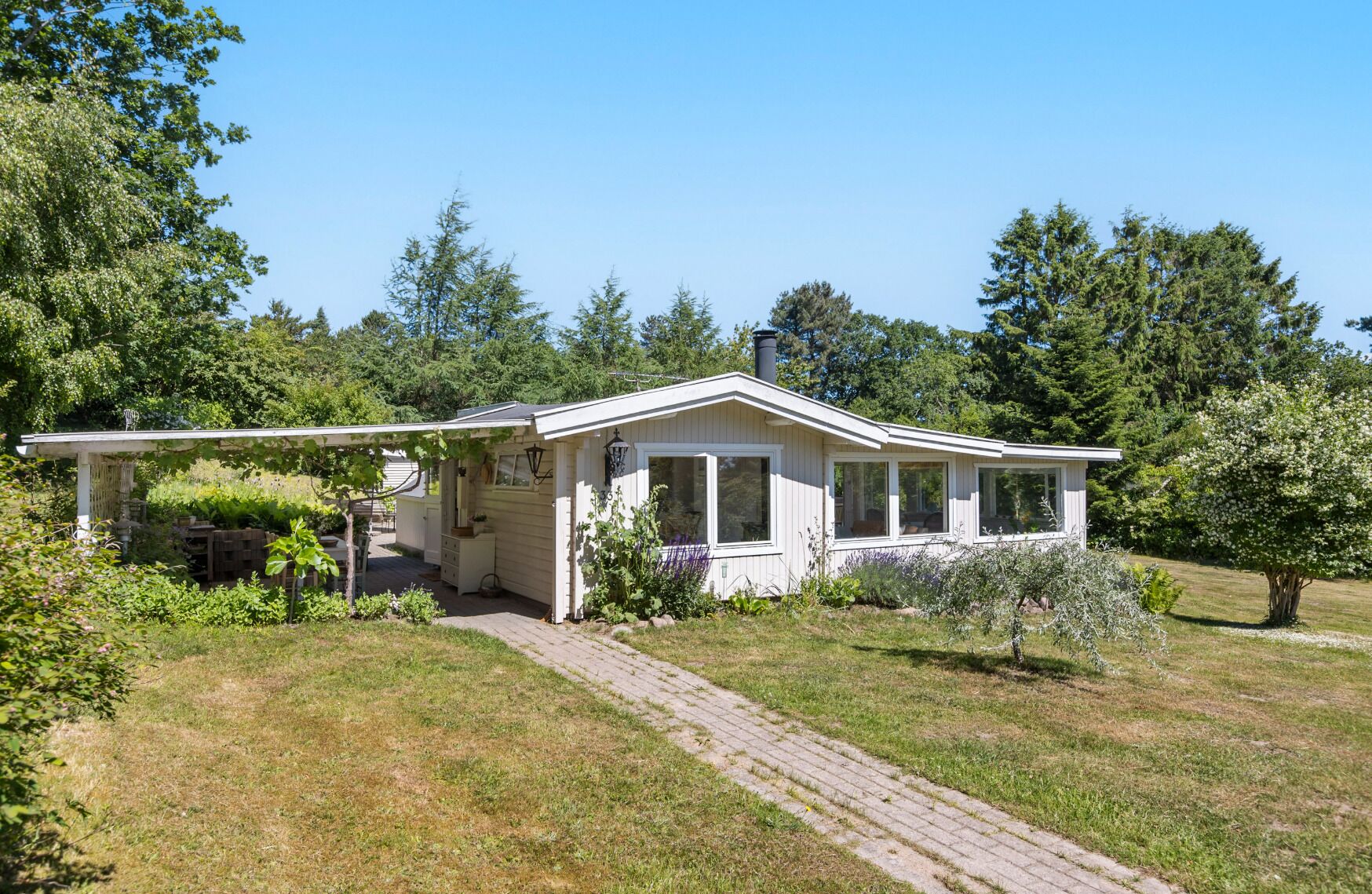 A single-story house with a covered porch, a small garden, and a paved driveway.