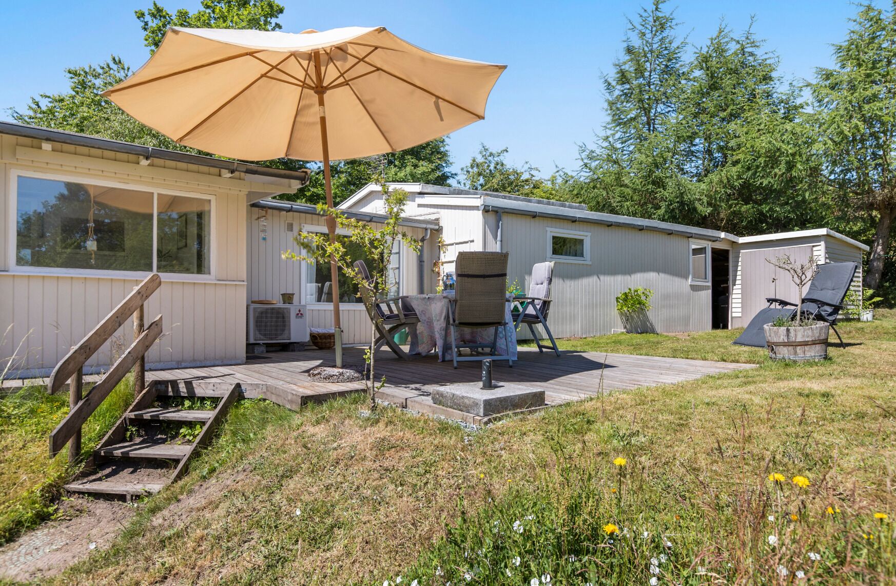 A mobile home with a patio area, outdoor seating, and a large umbrella.