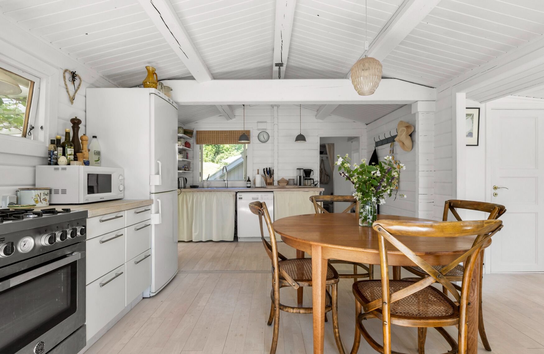 A kitchen with white cabinetry, a wooden dining table, and a stove.