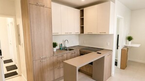 A modern kitchen with light wood cabinetry, a central island, and a built-in stove. - Charming studio at midtown (Miami)