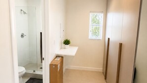 A narrow hallway with a shower, toilet, and a small window. - Charming studio at midtown (Miami)