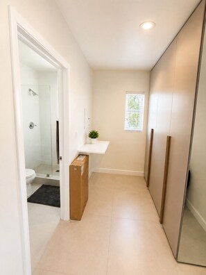 A narrow hallway with a shower, toilet, and a small window. - Charming studio at midtown (Miami)