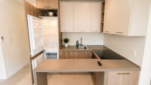 A modern kitchen with white cabinetry, a built-in oven, a sink, and a stove. - Charming studio at midtown (Miami)