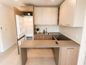 A modern kitchen with white cabinetry, a built-in oven, a sink, and a stove. - Charming studio at midtown (Miami)