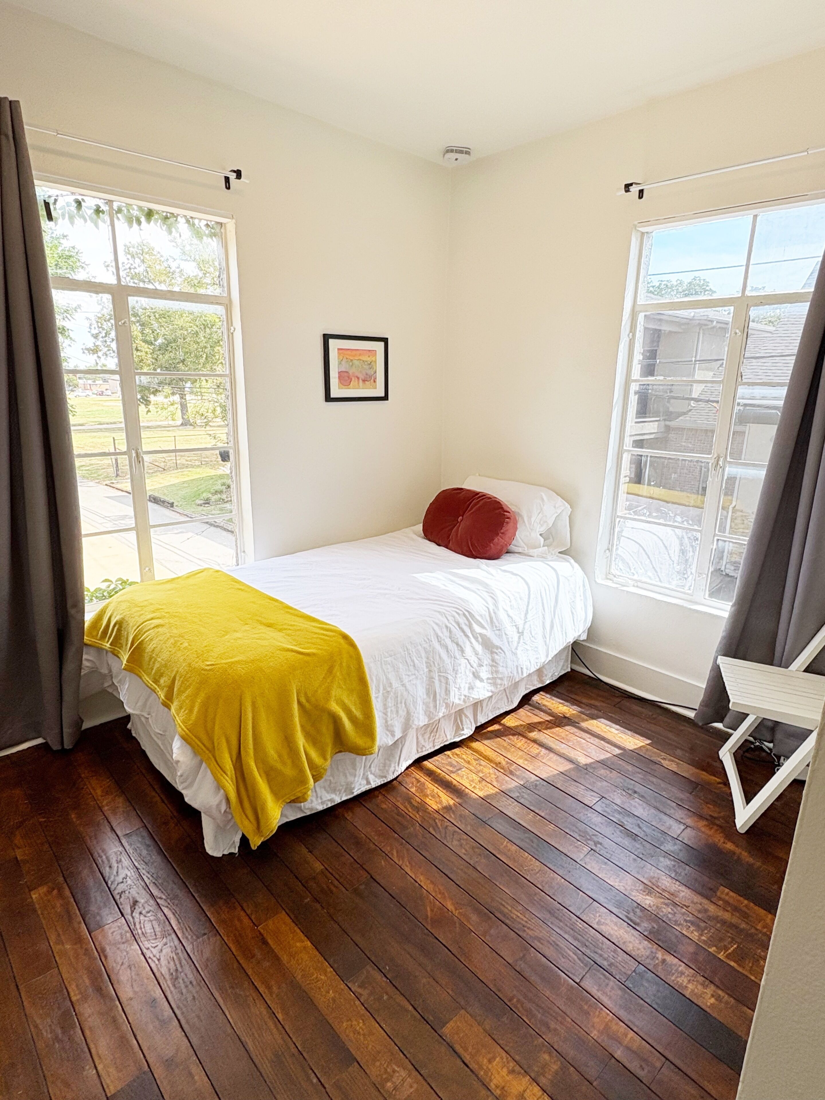 A bedroom with a bed, a window, and a picture on the wall.