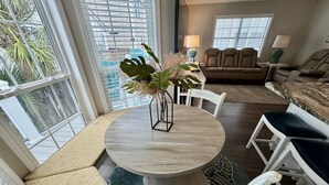 A dining area with a round table, white chairs, and a bench. - Ocean Views, Ocean Breeze and the Sound of Waves (Myrtle Beach)