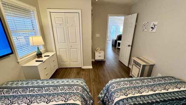 A bedroom with two beds, a dresser, a nightstand, and a window with blinds. - Ocean Views, Ocean Breeze and the Sound of Waves (Myrtle Beach)