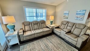 A living room with a beige sectional sofa, two side tables with lamps, a patterned rug, and artwork on the walls. - Ocean Lakes Ocean View Beach House | 4th House From Beach | Golf Cart | Sleeps 8 (Myrtle Beach)