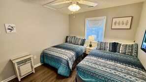 A bedroom with two beds, a ceiling fan, a window with blinds, and a wall-mounted TV. - Ocean Lakes Ocean View Beach House | 4th House From Beach | Golf Cart | Sleeps 8 (Myrtle Beach)