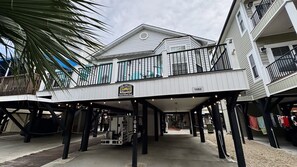 A beachfront property with a covered walkway, a sign indicating 'The Owens Beachy McBean House,' and a number '1082' on the structure. - Ocean Lakes Ocean View Beach House | 4th House From Beach | Golf Cart | Sleeps 8 (Myrtle Beach)