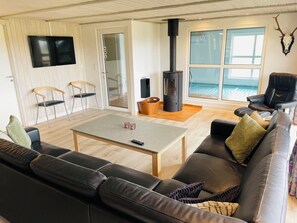 A modern living room with a sofa, a coffee table, a fireplace, and a television. - Spacious holiday home in West Jutland (Nørre Nebel)