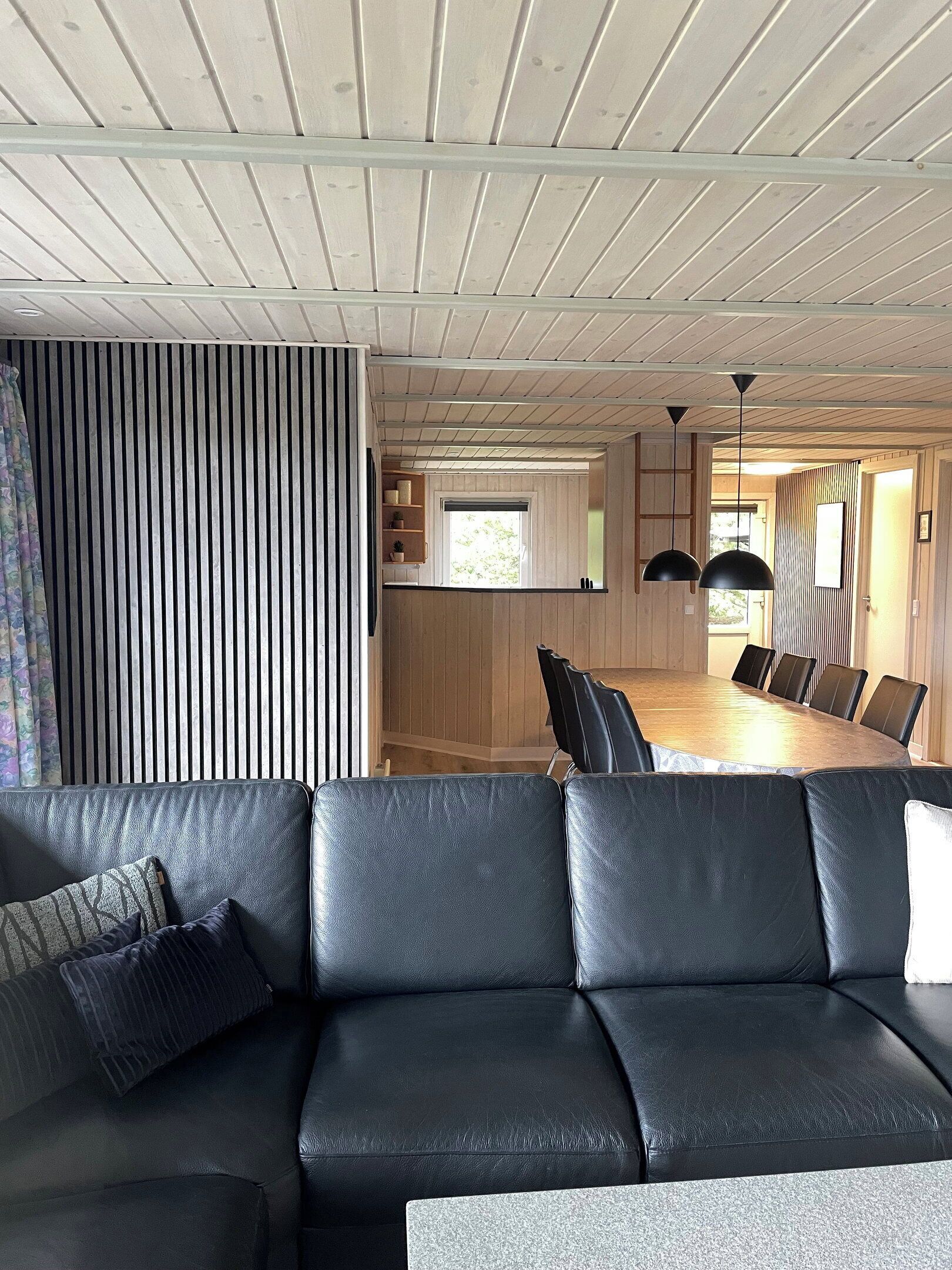 A modern interior with a sectional sofa, a dining table with chairs, and a kitchen area.