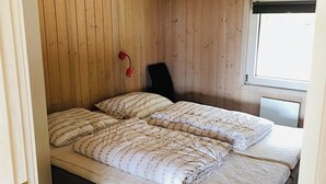 Une pièce avec un lit, une chaise et une fenêtre.