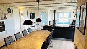 Une cuisine moderne avec un coin repas, une grande table et une vue sur l’océan.