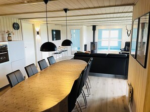 A modern kitchen with a dining area, a large table, and a view of the ocean. - Spacious holiday home in West Jutland (Nørre Nebel)