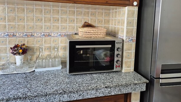 A kitchen with a built-in toaster oven, a stainless steel refrigerator, and a tiled backsplash.