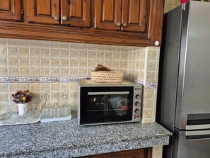 A kitchen with a built-in toaster oven, a stainless steel refrigerator, and a tiled backsplash.
