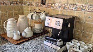 A kitchen with a coffee machine, white teapots, cups, and a tray.