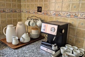 A kitchen with a coffee machine, white teapots, cups, and a tray.