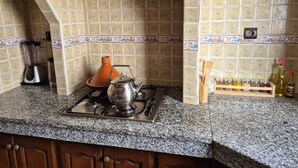 A kitchen with a gas stove, a blender, a kettle, and a spice rack. - Confort plus (Agadir)