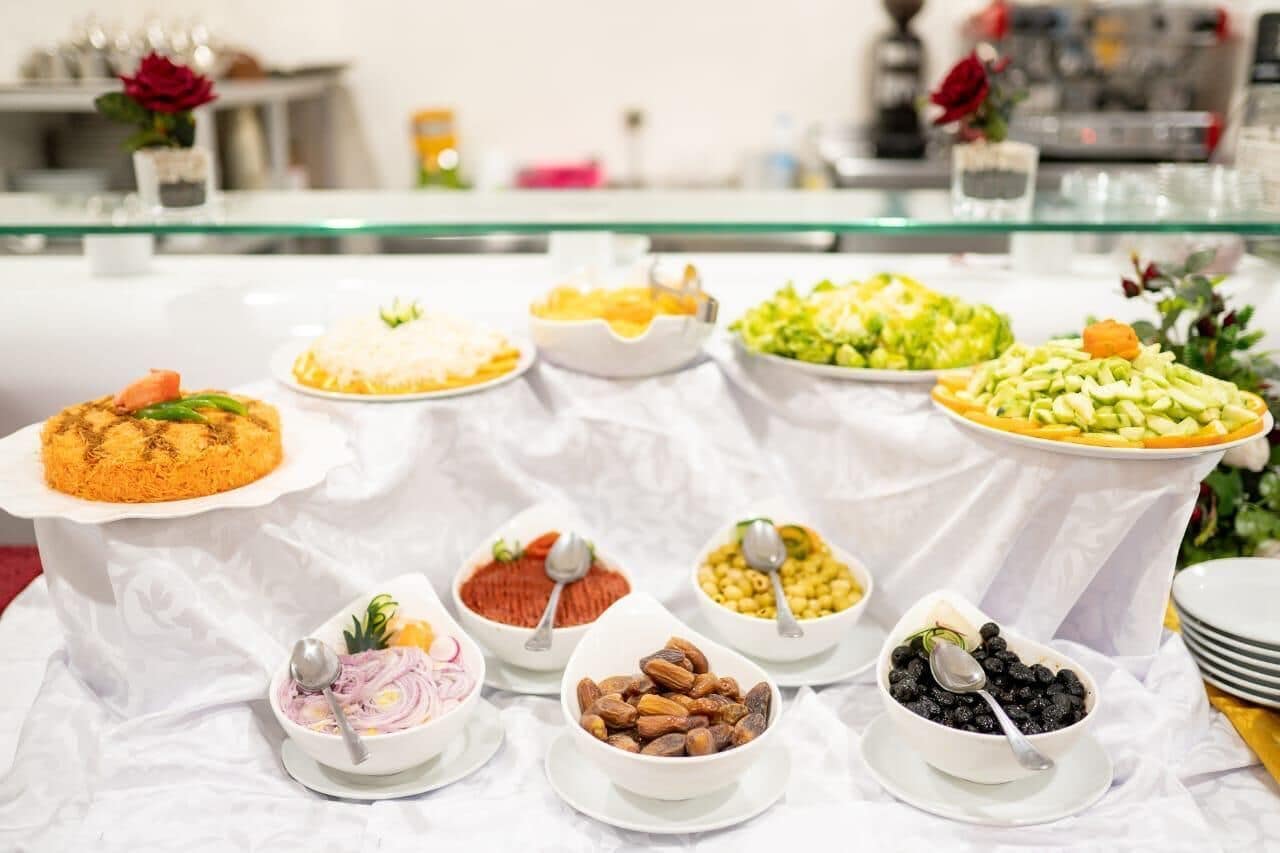 Ein reichhaltiges Buffet mit verschiedenen Speisen, darunter ein Reisgericht, Salat sowie Schalen mit Nüssen und Beeren.