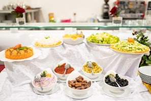 A buffet table with various dishes including a rice dish, a salad, and bowls of nuts and berries.