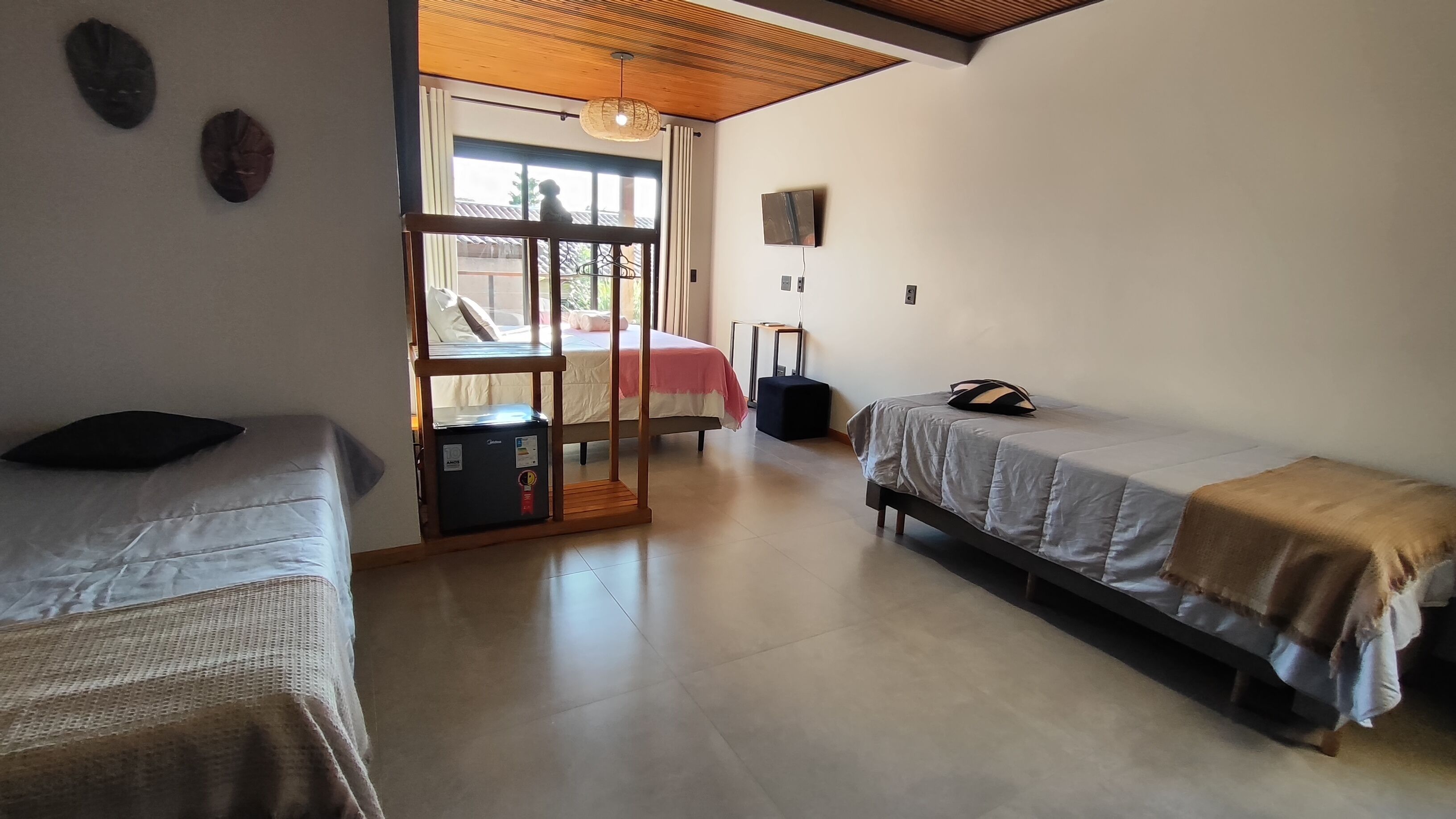 Une chambre avec deux lits, une petite table, un radiateur et une fenêtre avec des rideaux.