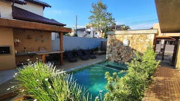 Una piscina con sillas de descanso, un muro de piedra y una escultura de cabeza de Buda.