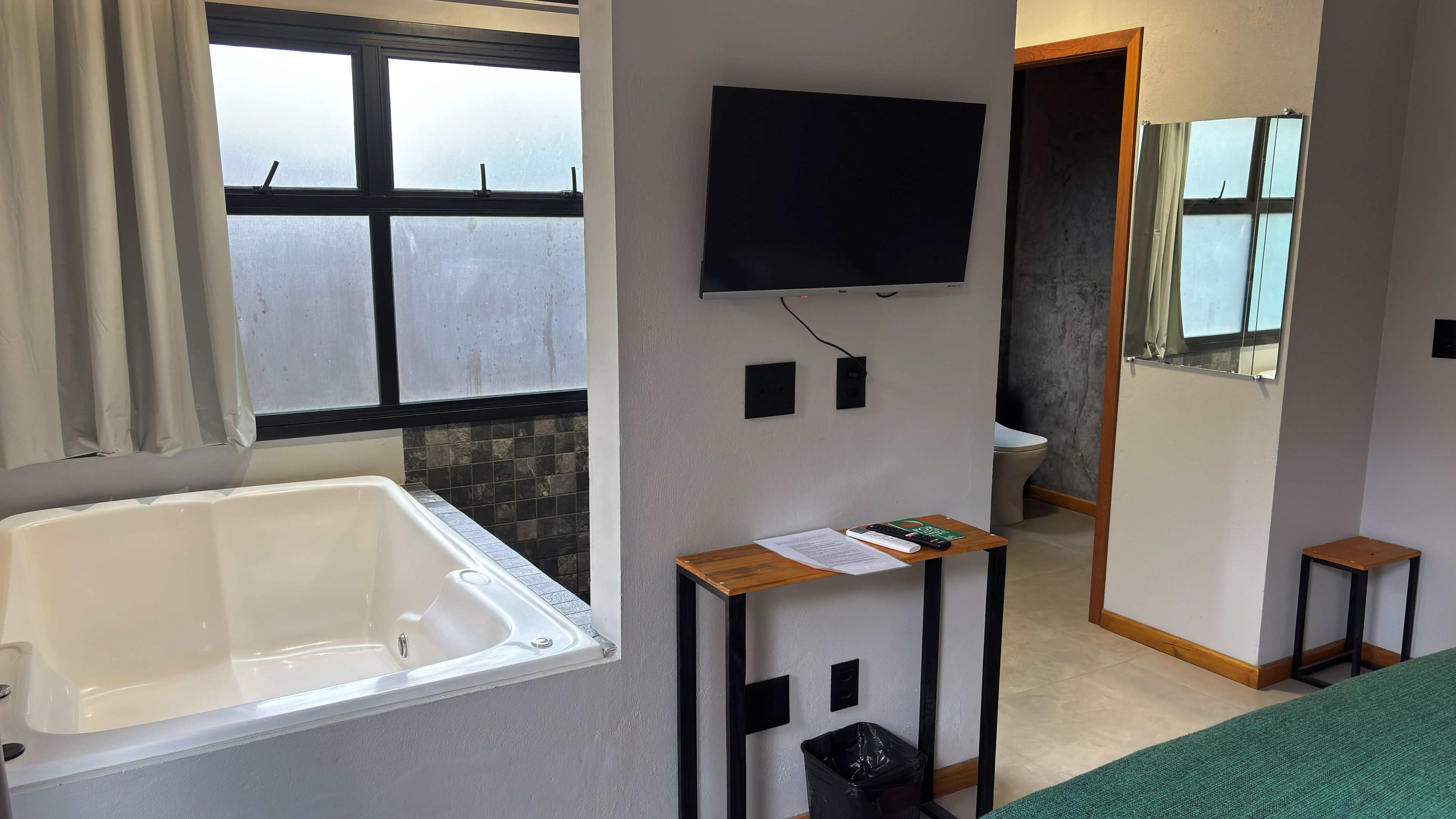 Un bagno con una vasca, un water, uno specchio e una televisione montata a parete.