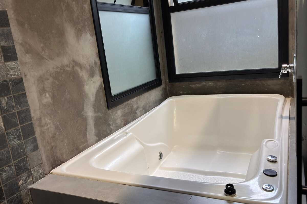 A bathroom with a white bathtub, a tiled wall, and a glass shower enclosure.