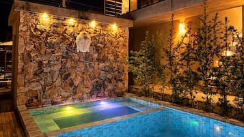 Una piscina con muro de piedra y cubierta de madera.