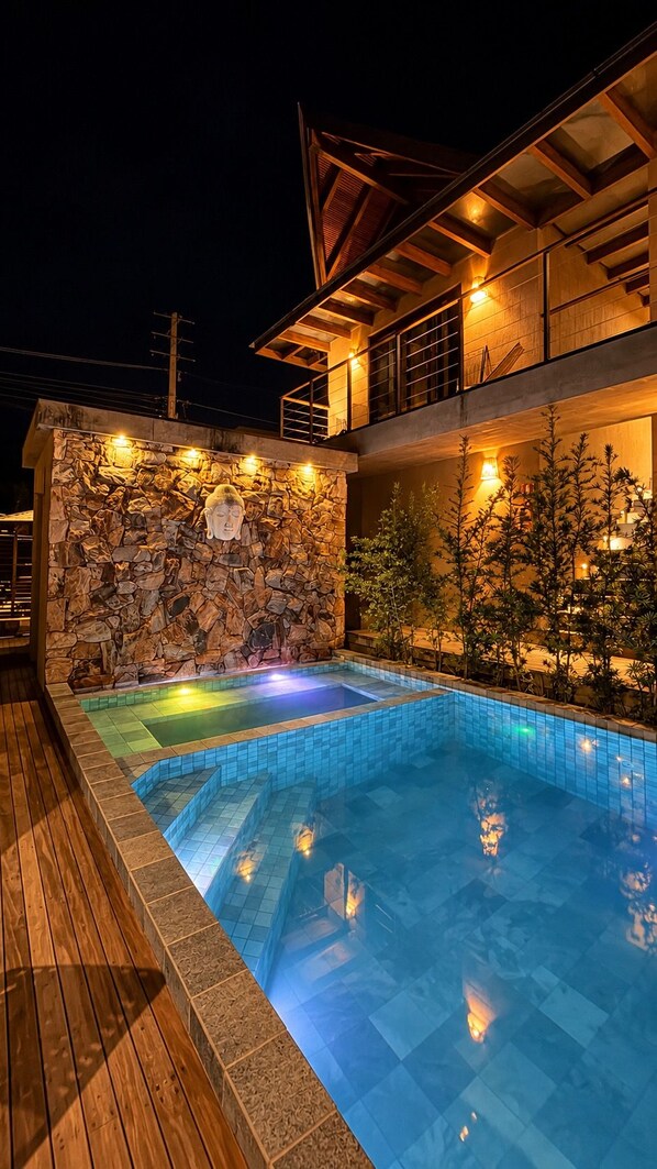 A swimming pool with a stone wall and wooden deck.