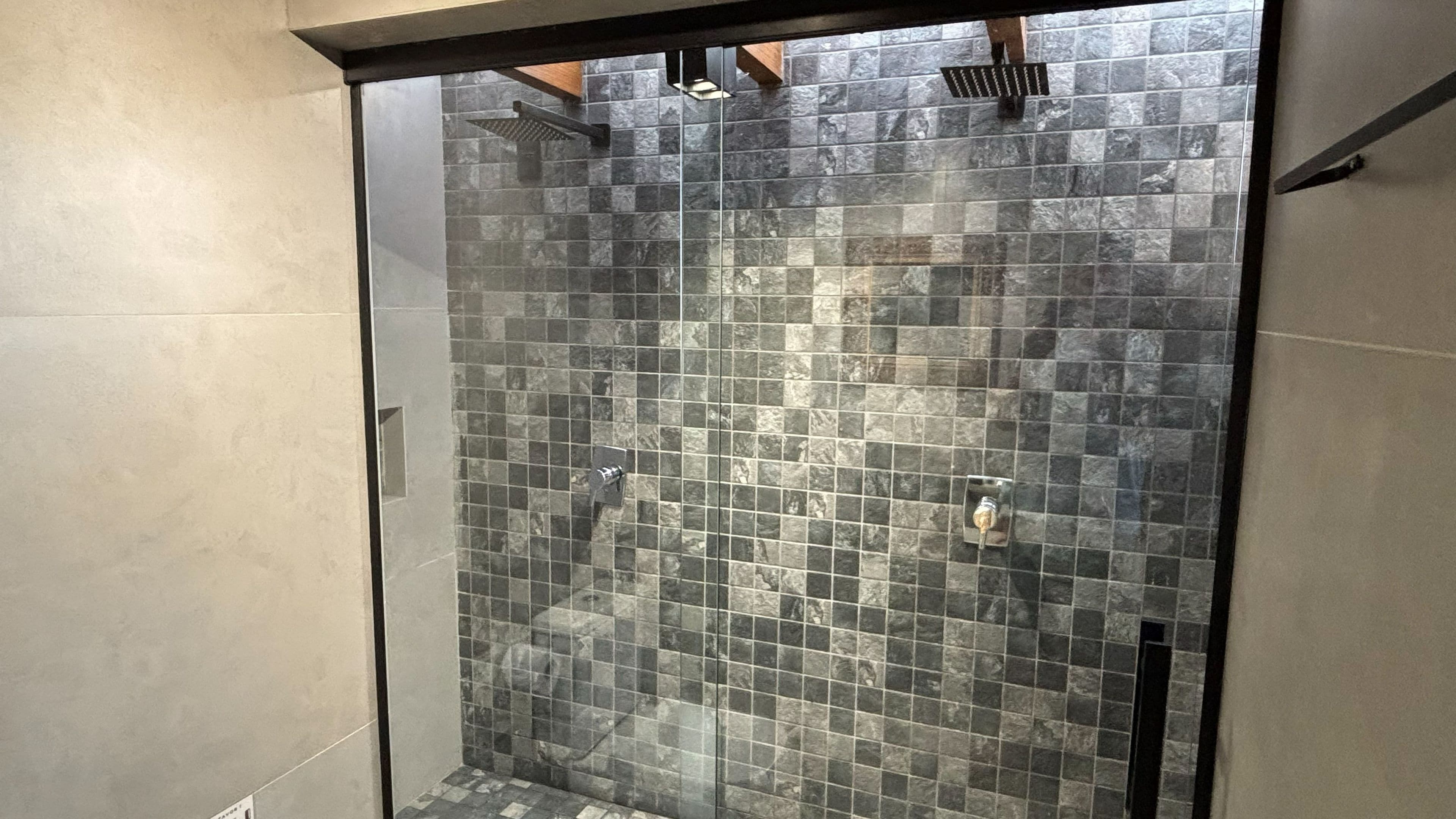A shower with a glass door and a tiled wall.